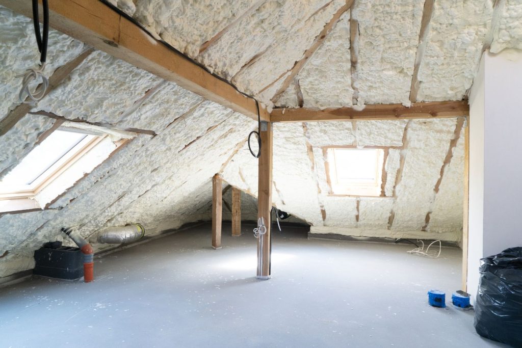 A room featuring exposed insulation and a loft area, showcasing a cozy and functional living space.