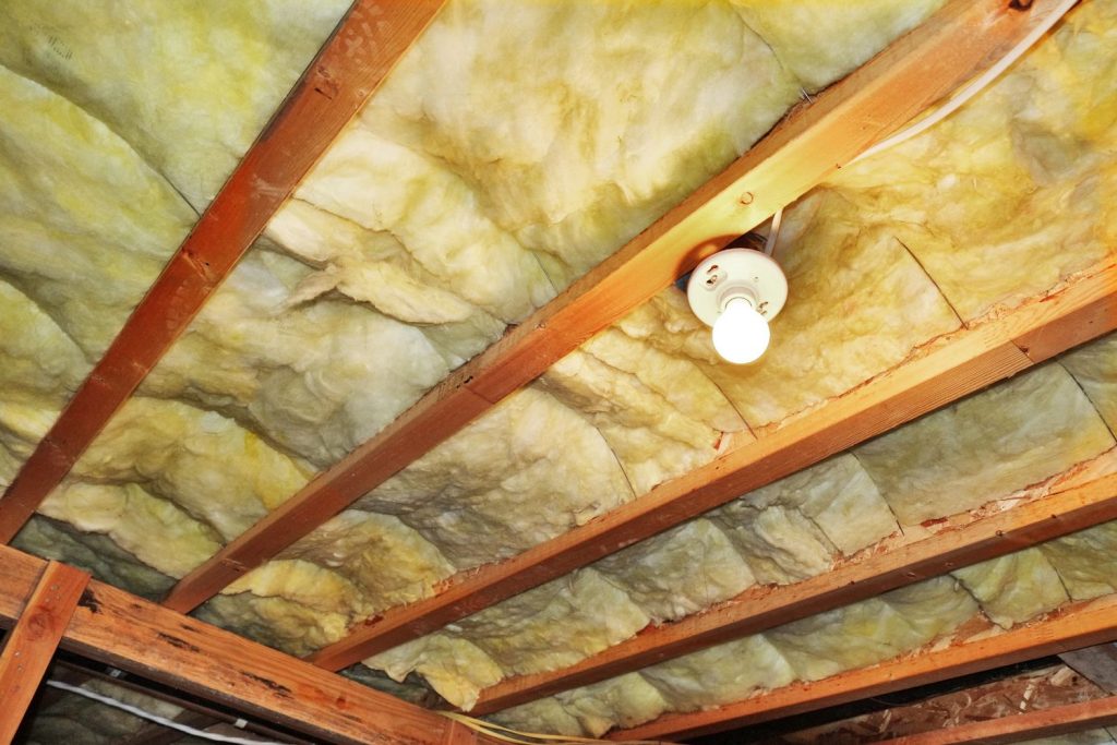 Interior view of a room with visible wood beams and insulation, highlighting a raw, industrial design.